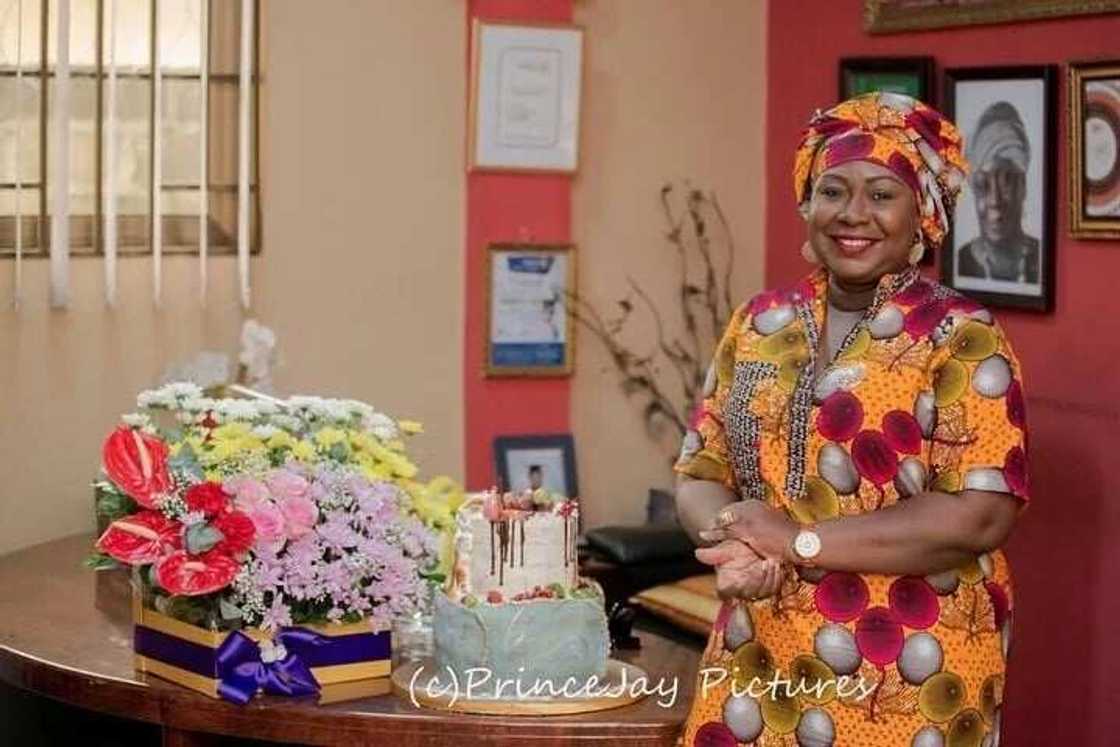 Gifty Anti standing next to a cake and a flower arrangement Gifty Anti standing next to a cake and a flower arrangement
