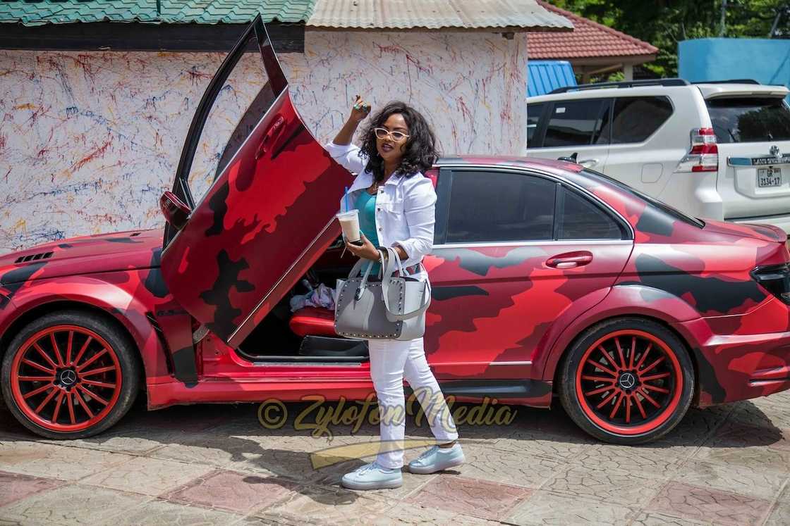 Nana Ama McBrown standing beside her BMW