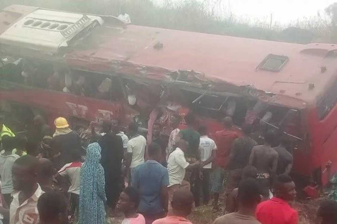 People surrounding an overturned bus