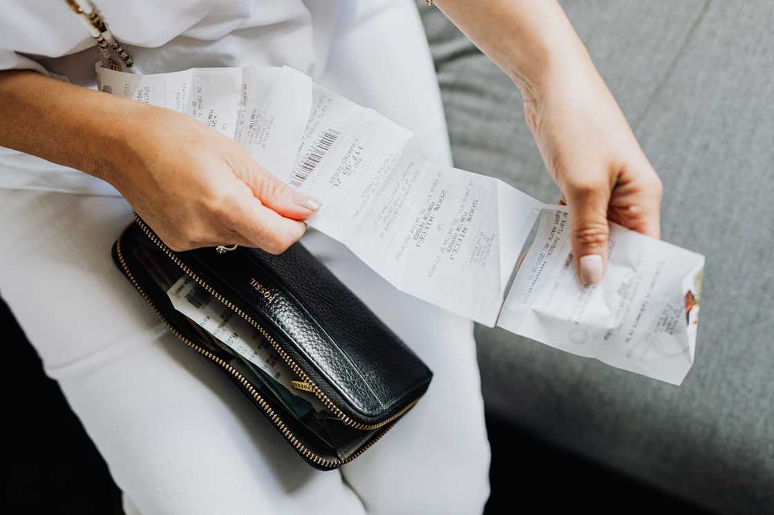 A person reviews several receipts next to an open wallet.