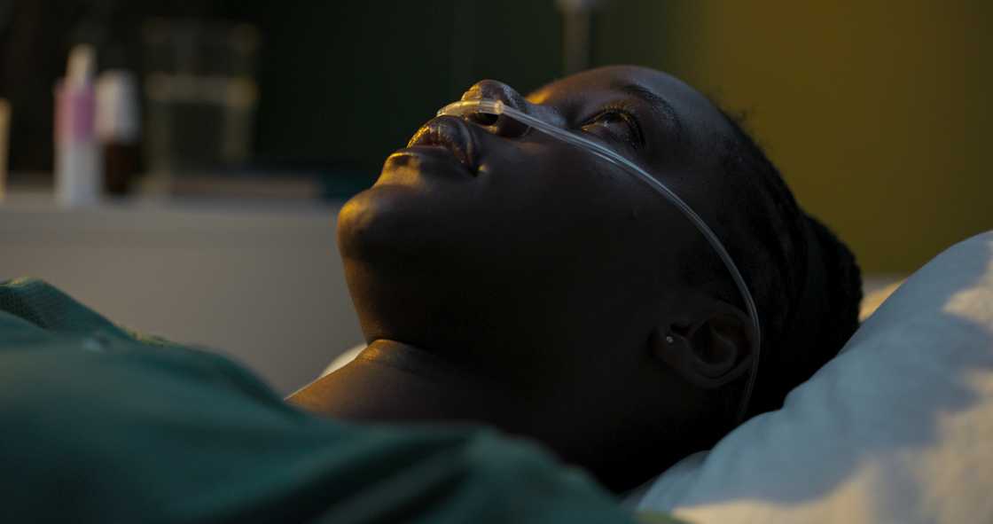 A woman lying in the ward wearing an oxygen tube