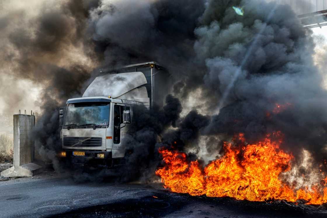 A truck headed towards Nablus drives past tyres set on fire by protesters in the occupied West Bank on November 1: the United Nations says recent months have been the deadliest period in years in the West Bank