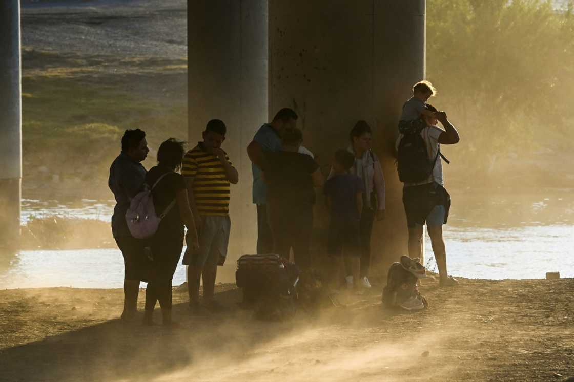 A migrant family from Venezuela waits to be apprehended by US authorities after crossing the border into Eagle Pass, Texas