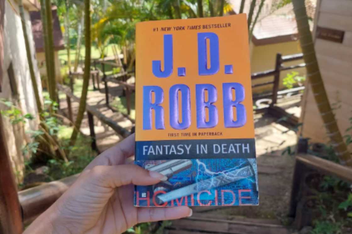 A person is holding a Fantasy in Death book A person is holding a Fantasy in Death book