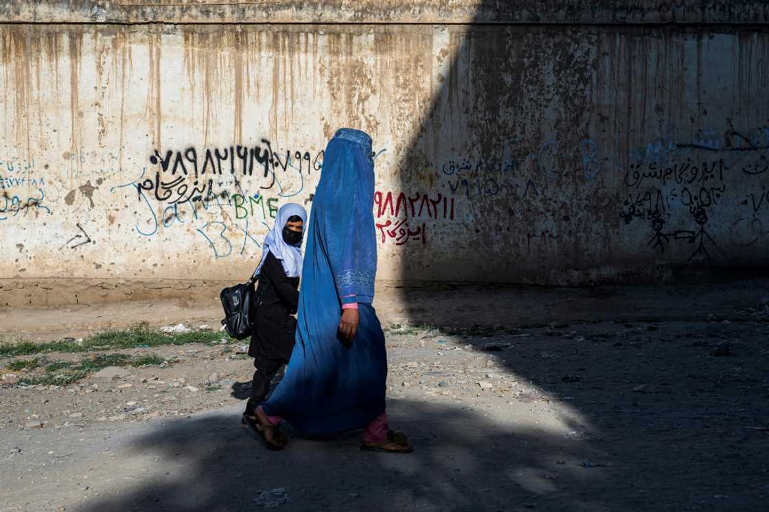 An Afghan woman walks a girl to a primary school in Kabul, though secondary education is now off-limits for young women under Taliban rule An Afghan woman walks a girl to a primary school in Kabul, though secondary education is now off-limits for young women under Taliban rule