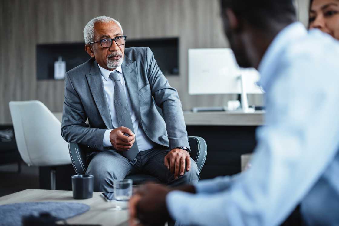 An older man confronts a lawyer in a Lagos office under a ceiling fan. An older man confronts a lawyer in a Lagos office under a ceiling fan.