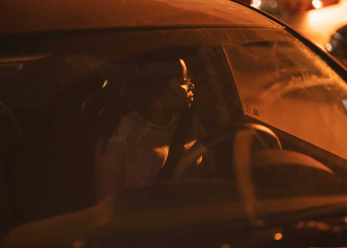 A woman sitting in the driver's seat of a car at night.