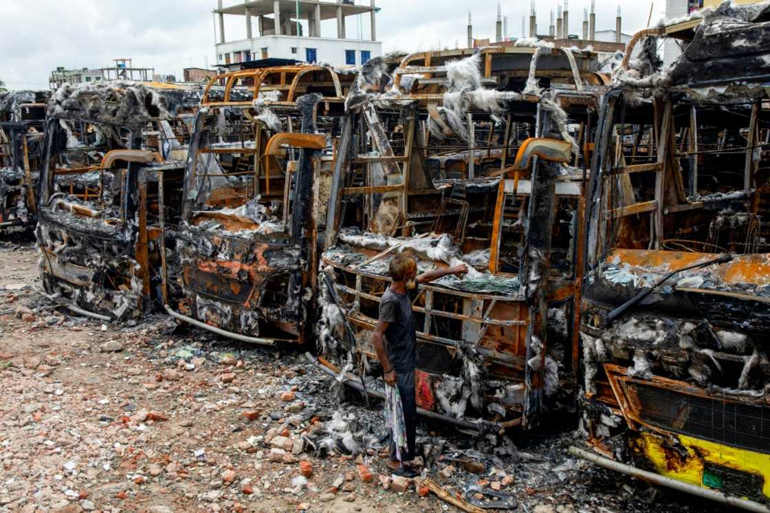 A man inspects burnt buses at a warehouse in Dhaka