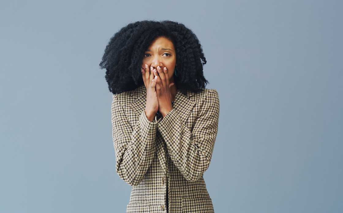A young woman looking surprised against a grey background A young woman looking surprised against a grey background