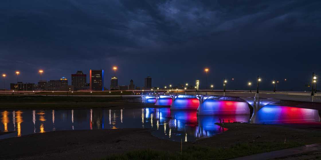 Illuminated Red White and Blue 5th Street Bridge crosses Miami River at night into Dayton, Ohio