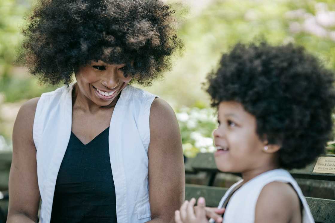 A woman and young child smiling together on a park bench. A woman and young child smiling together on a park bench.