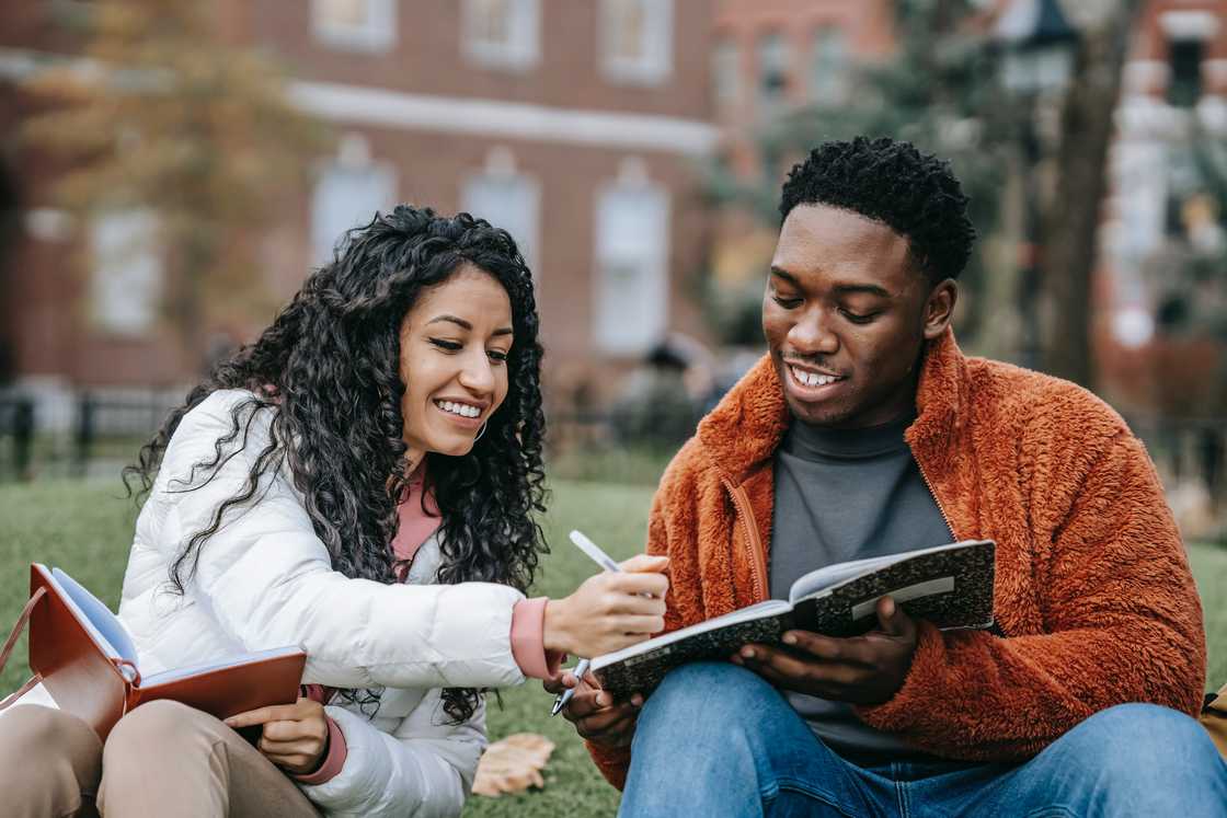 A man and a woman holding books while writing A man and a woman holding books while writing