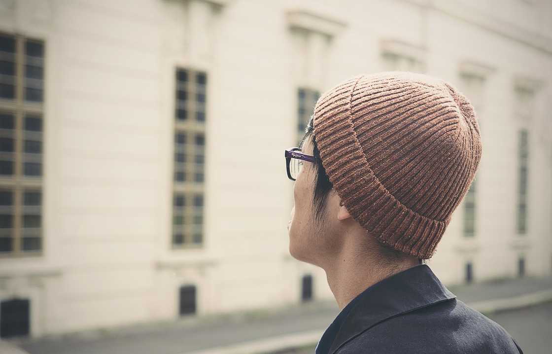 An Asian man in a black shirt and brown beanie An Asian man in a black shirt and brown beanie