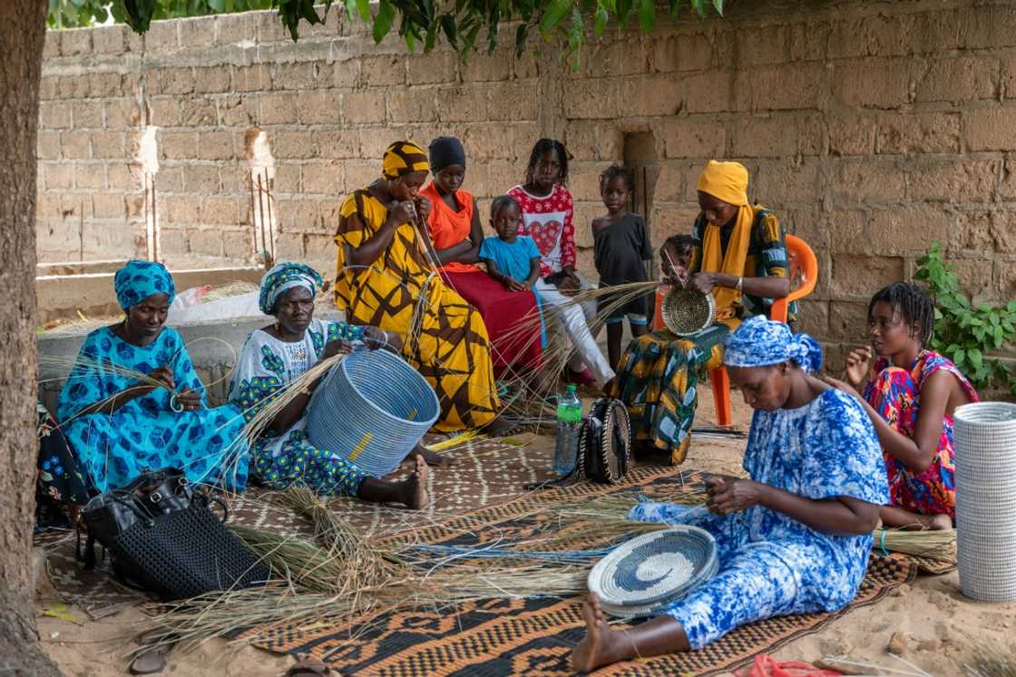 Women weave baskets using coloured recycled plastic strands under a mango tree in Khady Sene's courtyard in the village of Mborine, Senegal