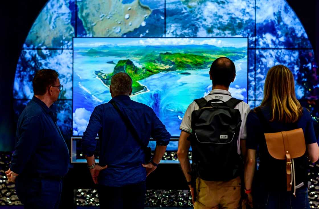 Visitors contemplate an 8K TV at the stand of South Korean consumer goods giant LG at the tech fair -- motto this year "energy efficiency" Visitors contemplate an 8K TV at the stand of South Korean consumer goods giant LG at the tech fair -- motto this year "energy efficiency"