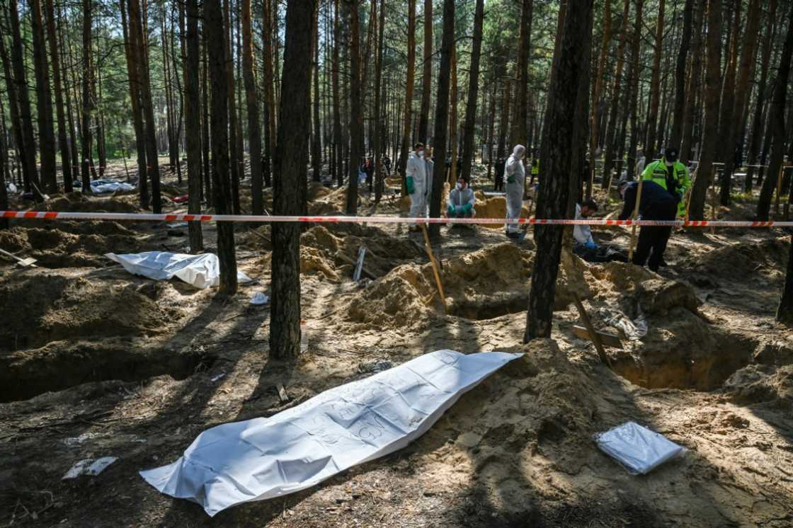 Forensic technicians exhume bodies and place them in body bags at a mass grave site on the outskirts of Izyum Forensic technicians exhume bodies and place them in body bags at a mass grave site on the outskirts of Izyum