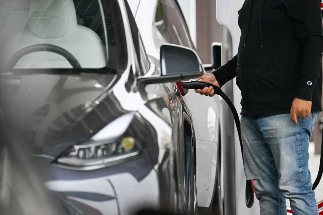 A driver plugs in a Tesla electric vehicle to charge at a Tesla Supercharger location in Santa Monica, California A driver plugs in a Tesla electric vehicle to charge at a Tesla Supercharger location in Santa Monica, California