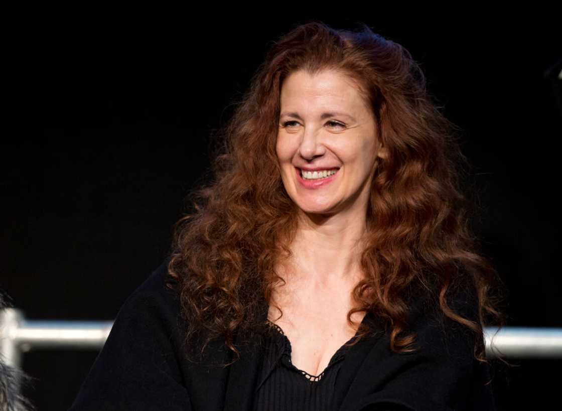 Suzie Plakson in curly copper hair and black attire as she attends a press conference in Germany