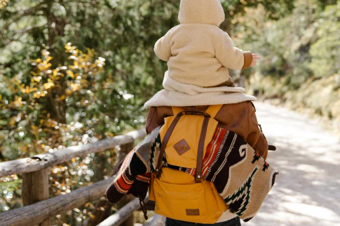 A man is carrying his child on his shoulder