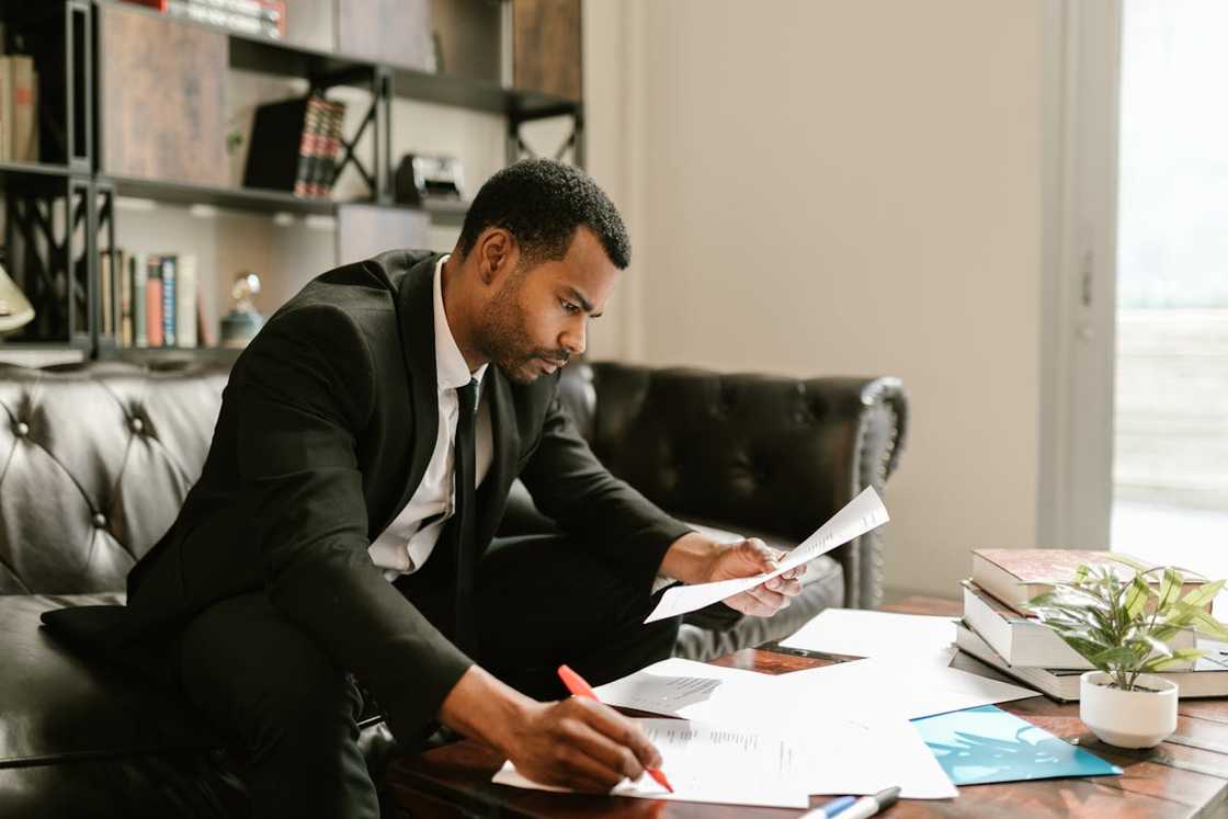 A businessman reviews documents and marking papers at a desk in an office. A businessman reviews documents and marking papers at a desk in an office.