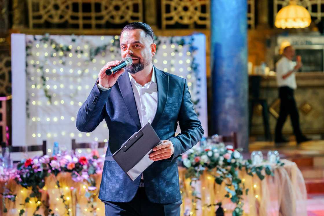 A man speaking at a decorated event. A man speaking at a decorated event.
