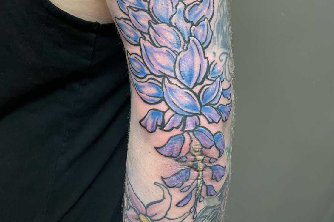A striking blue floral elbow tattoo A striking blue floral elbow tattoo