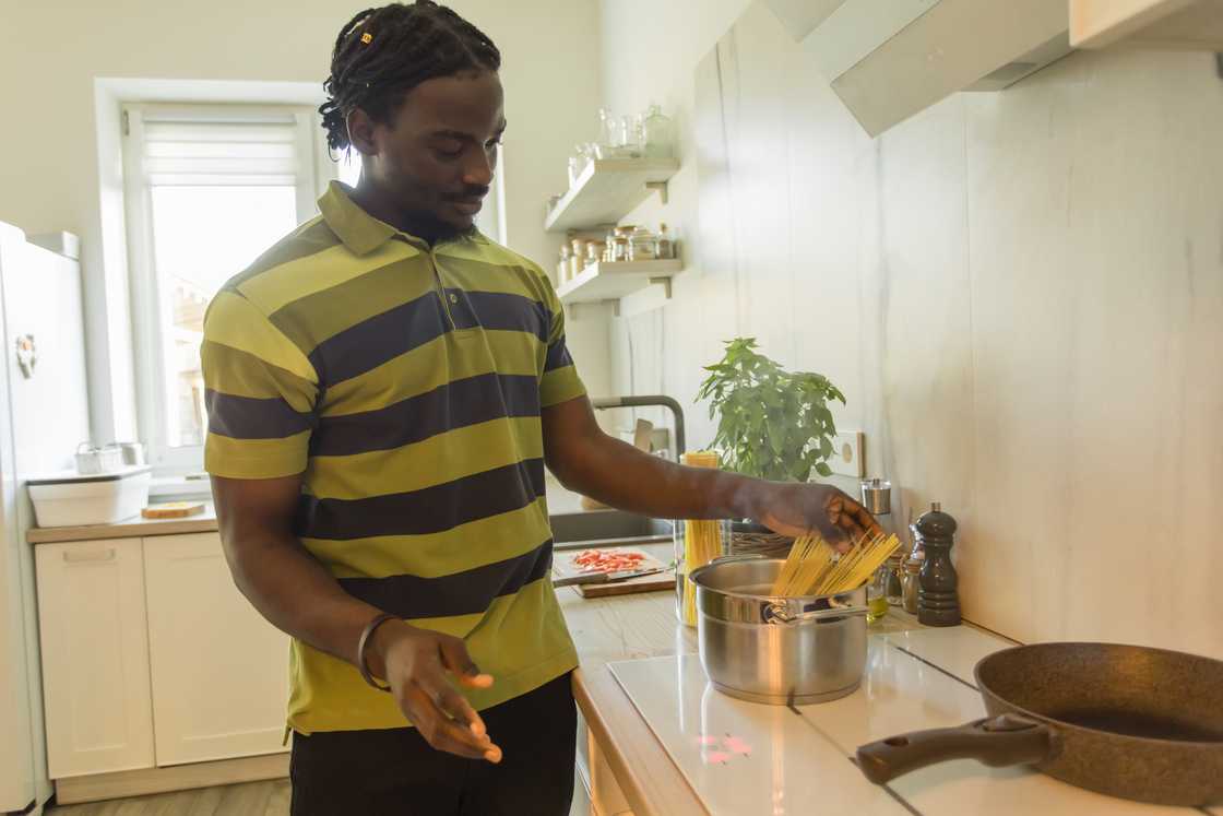 A young man cooking spaghetti by himself.