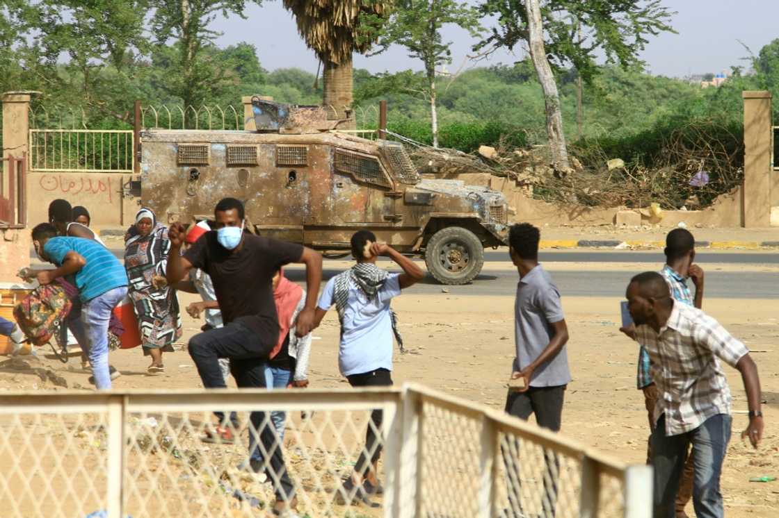 Sudanese anti-coup demonstrators duck for cover as a police vehicle fires tear gas in a street in the capital's twin city of Omdurman Sudanese anti-coup demonstrators duck for cover as a police vehicle fires tear gas in a street in the capital's twin city of Omdurman