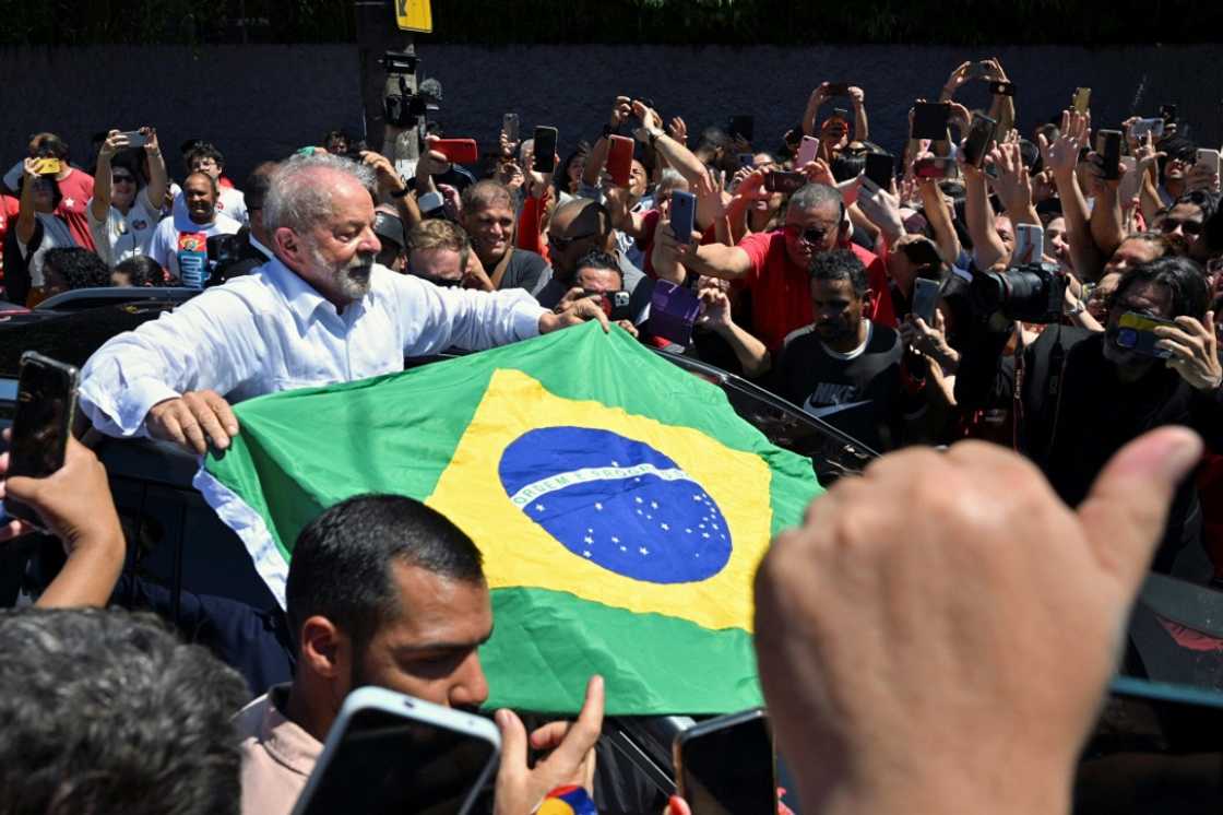Brazilian former president and candidate for the leftist Workers Party (PT) Luiz Inacio Lula da Silva unfolds a Brazilian flag while leaving the polling station during the presidential run-off election on October 30, 2022 Brazilian former president and candidate for the leftist Workers Party (PT) Luiz Inacio Lula da Silva unfolds a Brazilian flag while leaving the polling station during the presidential run-off election on October 30, 2022
