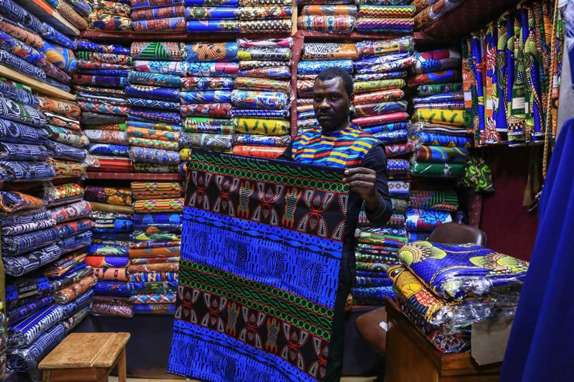 Iridescent: A trader holds a piece of the bright blue ndop ceremonial cloth in Bafoussam market in Cameroon Iridescent: A trader holds a piece of the bright blue ndop ceremonial cloth in Bafoussam market in Cameroon