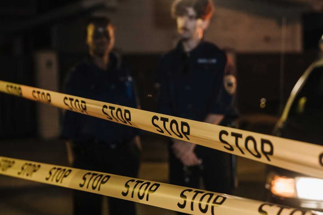 A police barrier blocks a street while officers stand behind it.