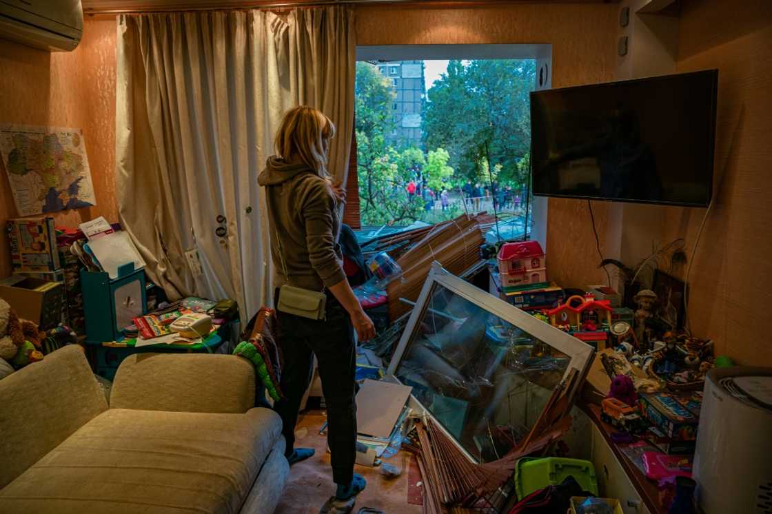 A woman looks out of a broken window of a damaged apartment A woman looks out of a broken window of a damaged apartment