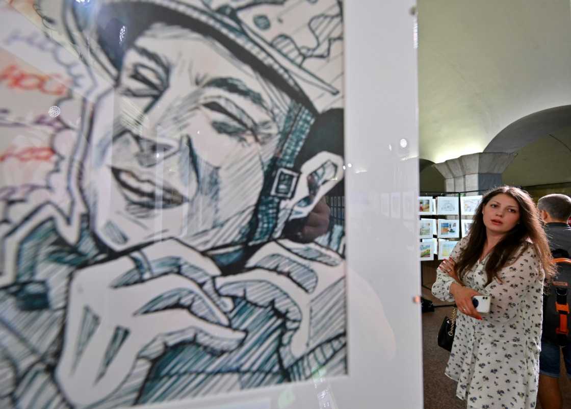 In one drawing, a smiling soldier straps on a helmet In one drawing, a smiling soldier straps on a helmet