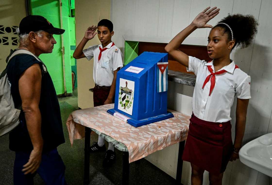 Students salute after a man cast his vote on a new, more liberal Family Code at a polling station in Havana, Cuba on September 25, 2022