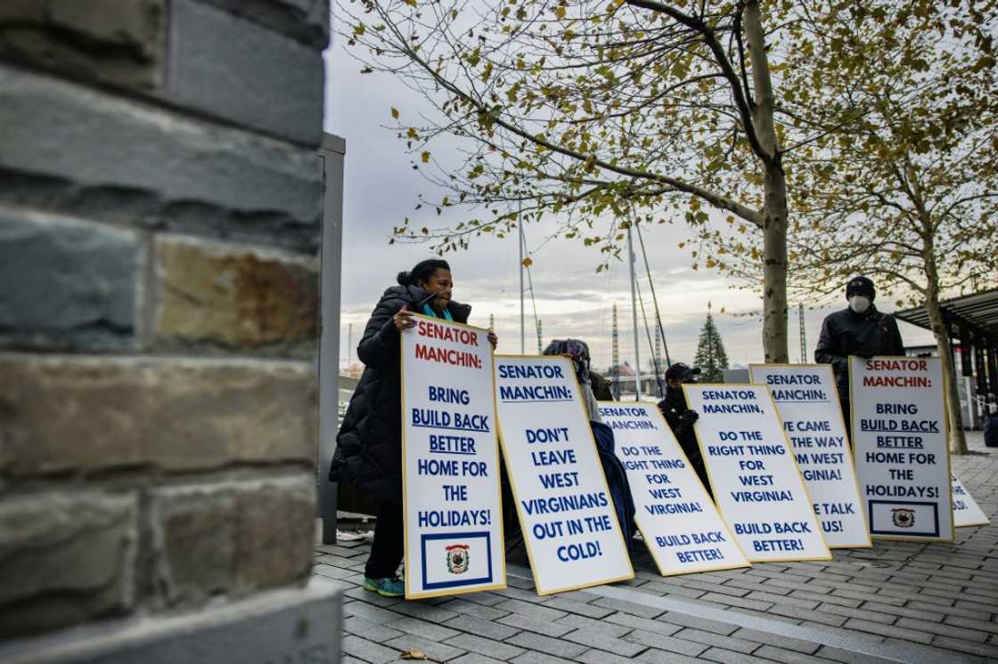 Activists with the Center for Popular Democracy hold signs near the entrance where Senator Joe Manchin's boat is docked in Washington in December 2021 Activists with the Center for Popular Democracy hold signs near the entrance where Senator Joe Manchin's boat is docked in Washington in December 2021