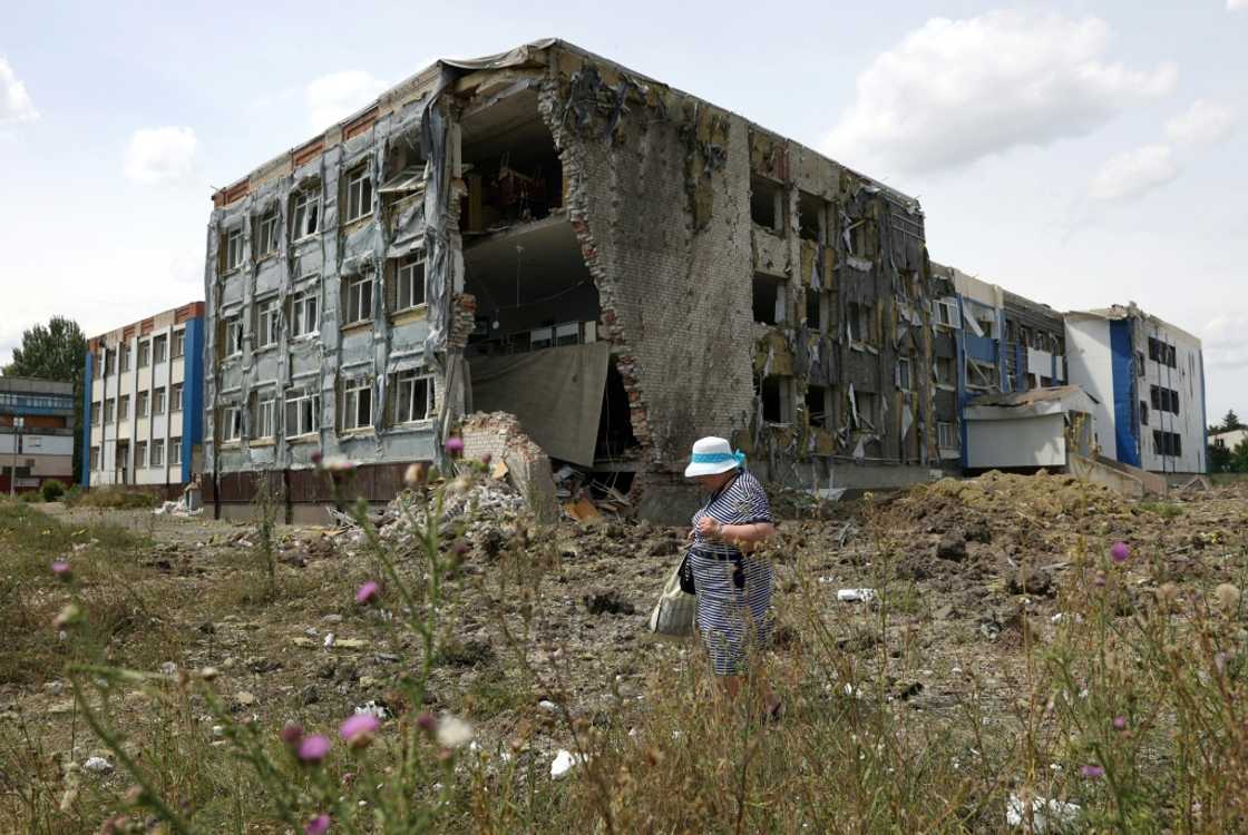 A woman walks past a school partially destroyed by a missile A woman walks past a school partially destroyed by a missile