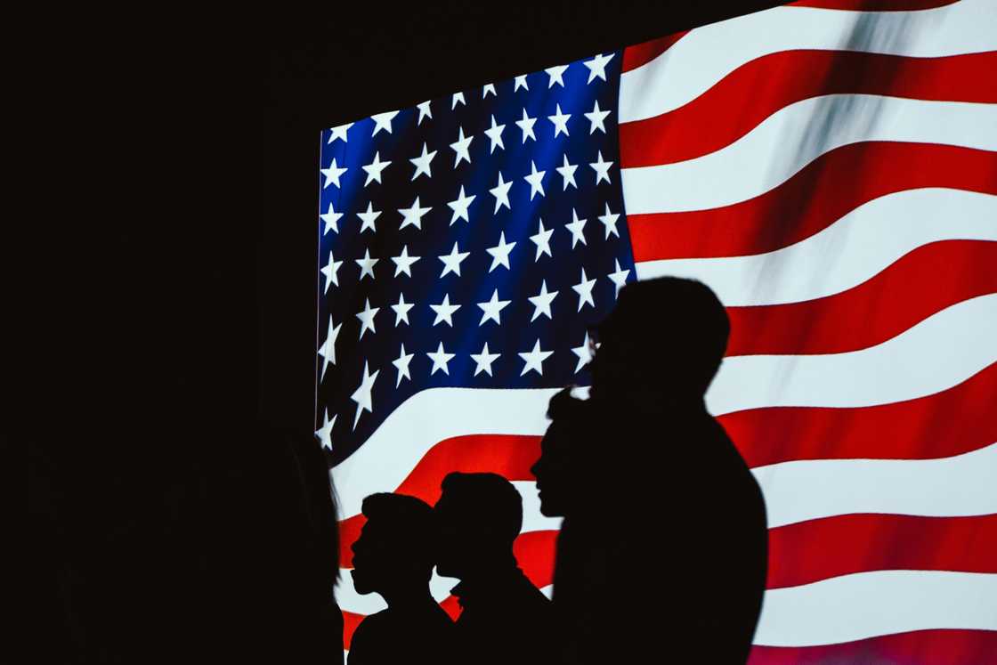 A silhouette of people beside the USA flag