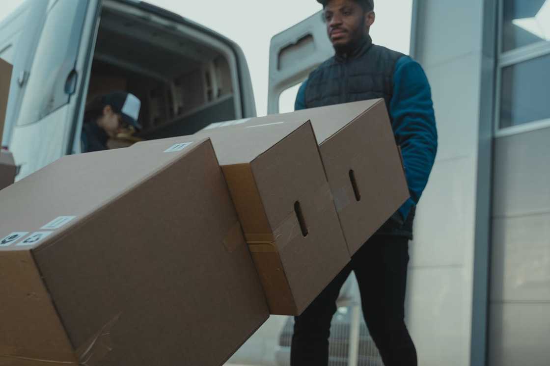 A delivery worker carrying stacked boxes from a van.
