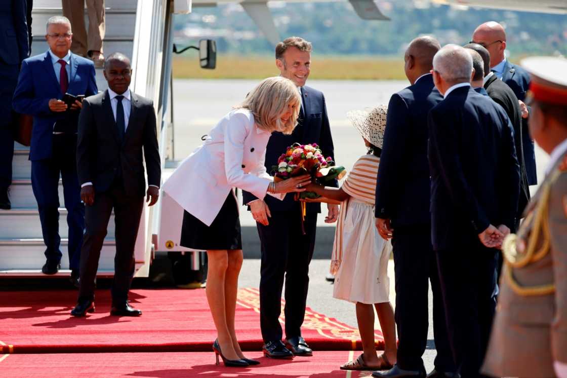 Macron and his wife Brigitte were greeted at the airport by flag-waving children before heading into the capital Antananarivo Macron and his wife Brigitte were greeted at the airport by flag-waving children before heading into the capital Antananarivo