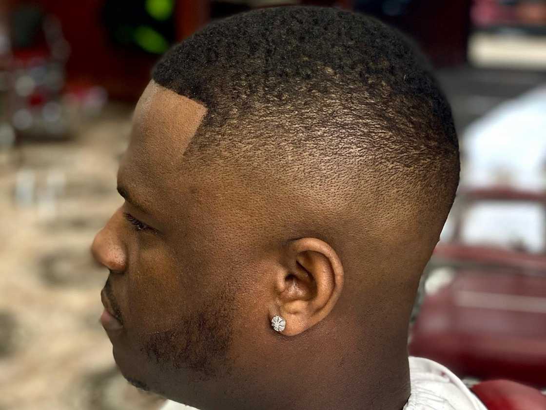 An African man in a barber shop has just received a high fade haircut