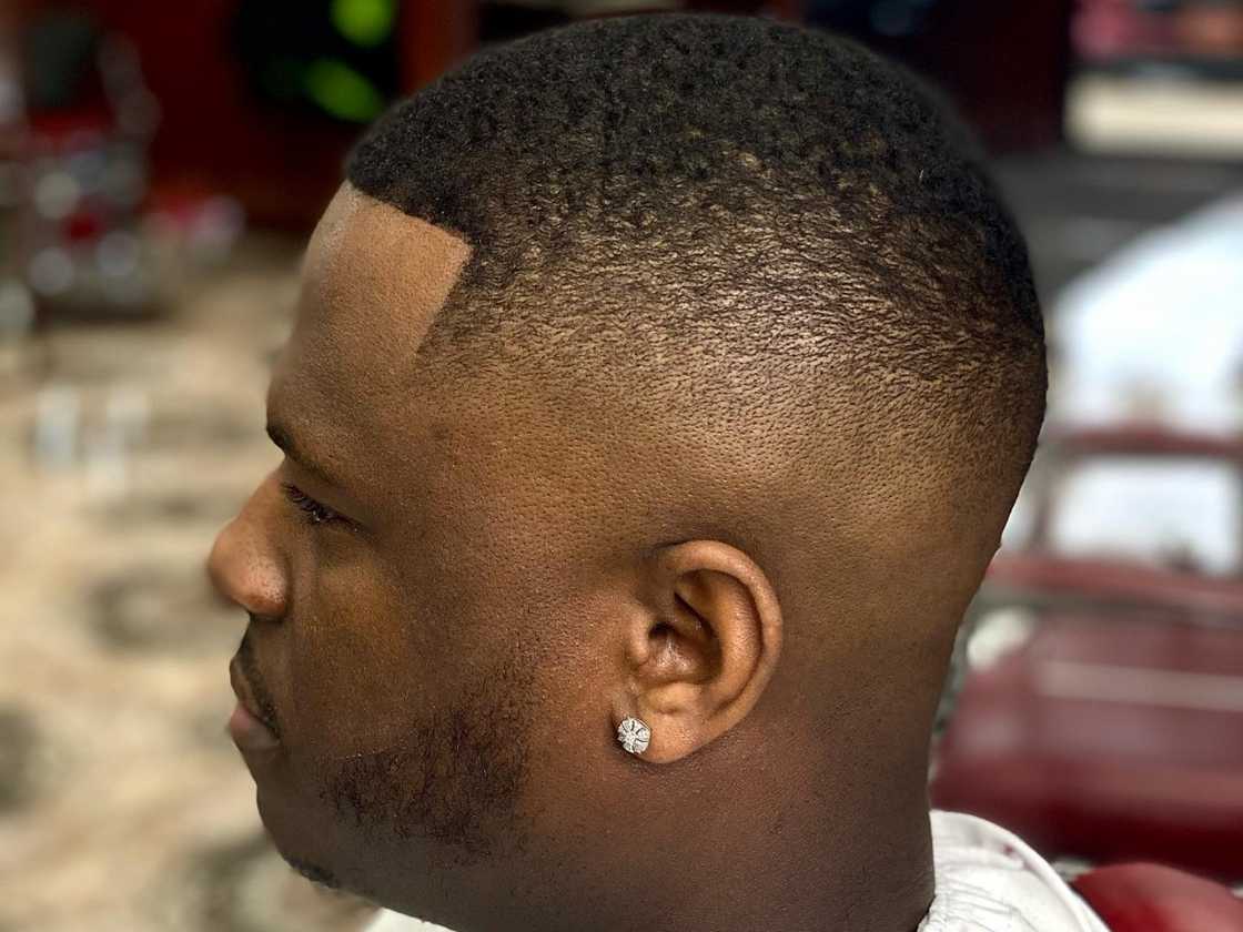 An African man in a barber shop has just received a high fade haircut An African man in a barber shop has just received a high fade haircut