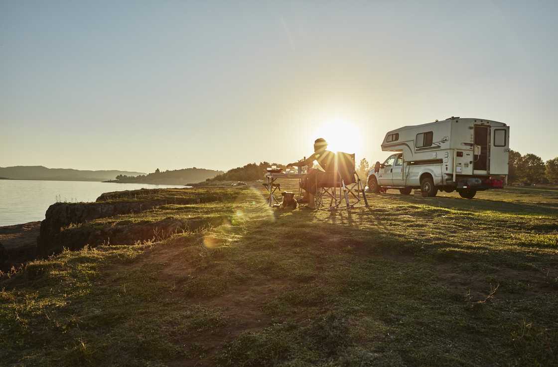 At sunset, a camper at the lake with a woman and dog in Talca, Rio Maule, Chile.