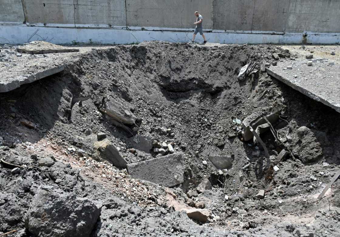 A man walks past a crater after a Russian rocket struck an industrial zone of Kharkiv on June 30, 2022 A man walks past a crater after a Russian rocket struck an industrial zone of Kharkiv on June 30, 2022
