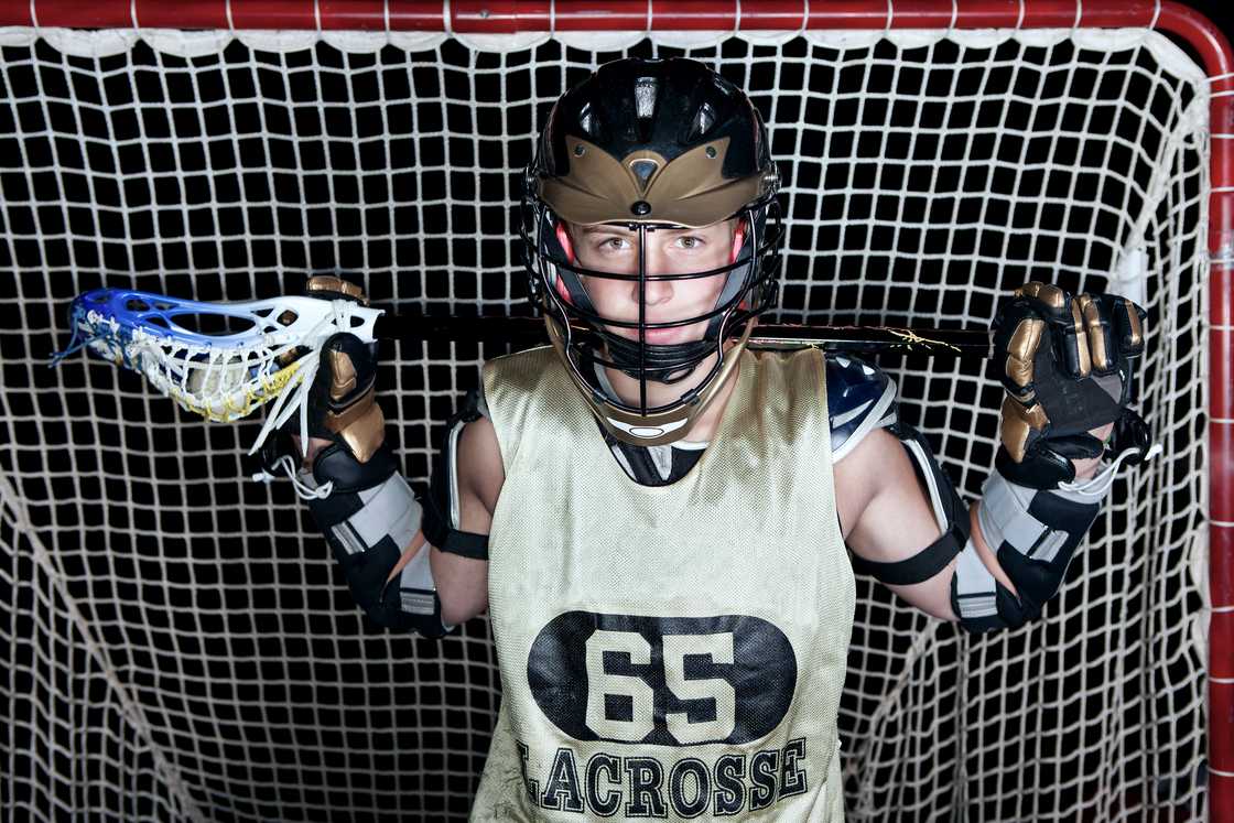 Lacrosse player dressed in uniform, holding a stick. Lacrosse player dressed in uniform, holding a stick.