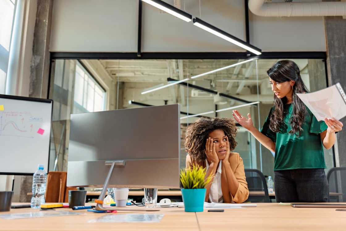 A businesswoman stands while arguing with a colleague