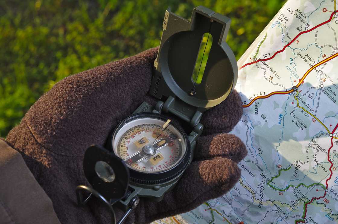 A person handles a military compass and map. A person handles a military compass and map.