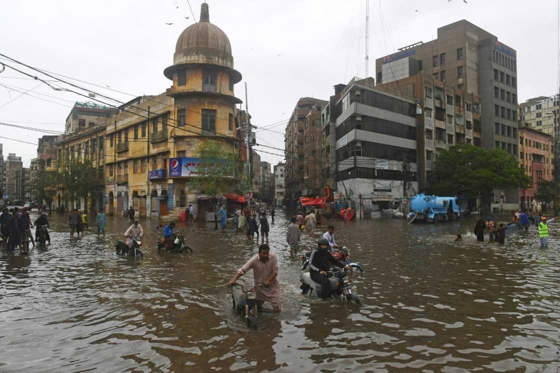 Motorcyclists push their vehicles through a flooded street in Pakistan's port city of Karachi Motorcyclists push their vehicles through a flooded street in Pakistan's port city of Karachi