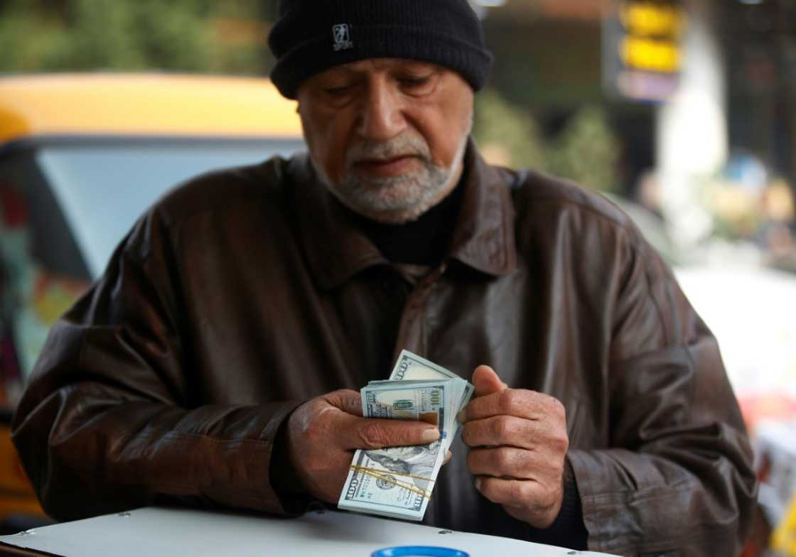 A man counts US dollar banknotes in a Baghdad market on December 27, 2022 as the value of Iraqi dinar against US dollar drops further. A man counts US dollar banknotes in a Baghdad market on December 27, 2022 as the value of Iraqi dinar against US dollar drops further.