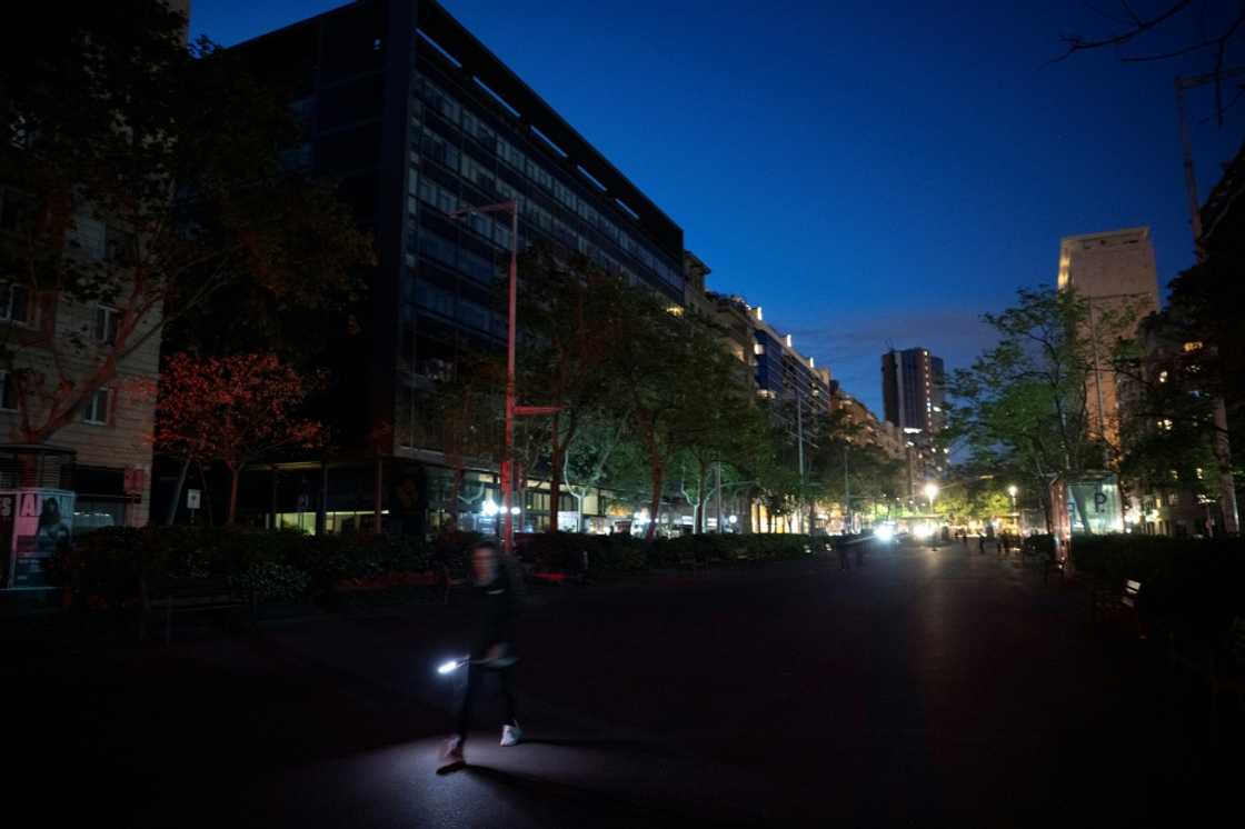 A pedestrian uses a flashlight to walk in a street of Barcelona on April 28, 2025 A pedestrian uses a flashlight to walk in a street of Barcelona on April 28, 2025
