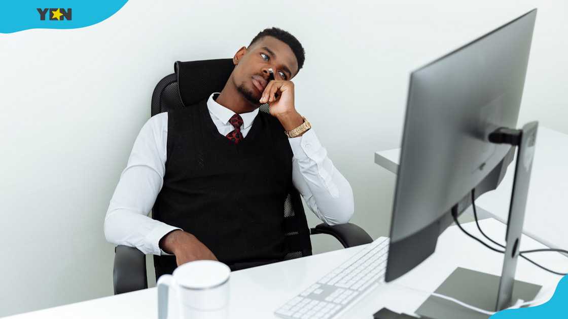 A man in a black vest and white dress shirt is sitting on a black chair